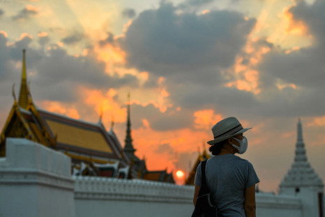 A tourist wears a face mask to prevent spread of the coronavirus disease during sunset near the Grand Palace in Bangkok