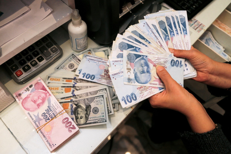 A money changer holds Turkish lira banknotes at a currency exchange office in Ankara