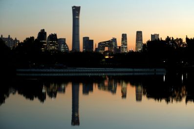 The cityscape of the Beijing Central Business District is reflected in a pond during sunset