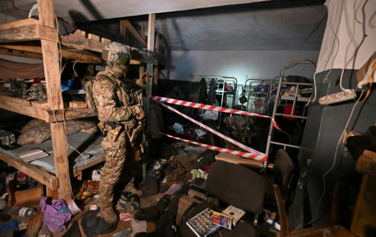 Inside one dark room, belongings and clothes look hastily abandoned, scrunched up on the floor and on the metal bunk beds with no mattresses