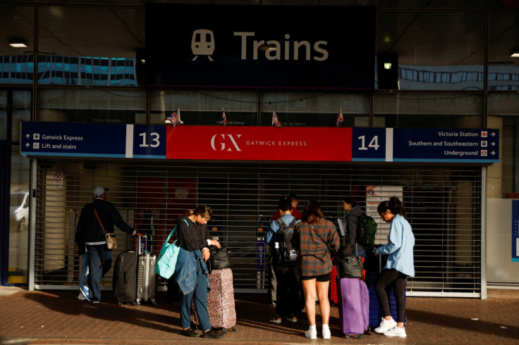 Travellers stand outside the closed entrance to the Gatwick Express train service at Victoria Station in London