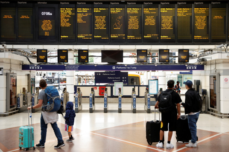 People look at the departures board at Victoria Station, in London