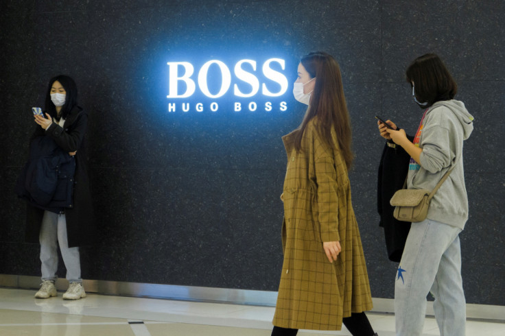 People walk past a store of German fashion house Hugo Boss in Beijing