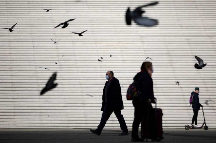 People, wearing protective face masks, walk past the steps near the Grande Arche in La Defense