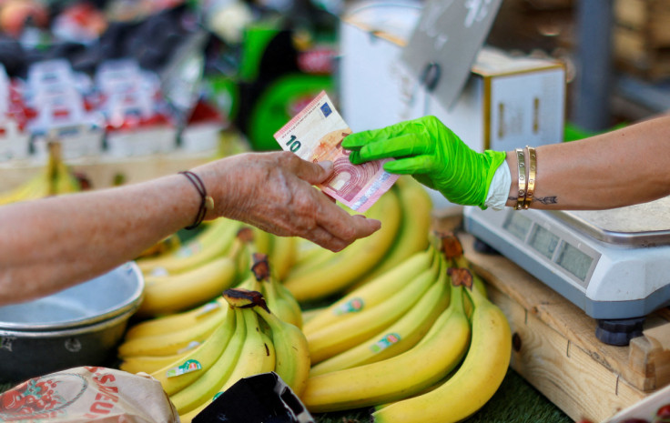 A shopper pays with a ten Euro bank note at a local market in Nice