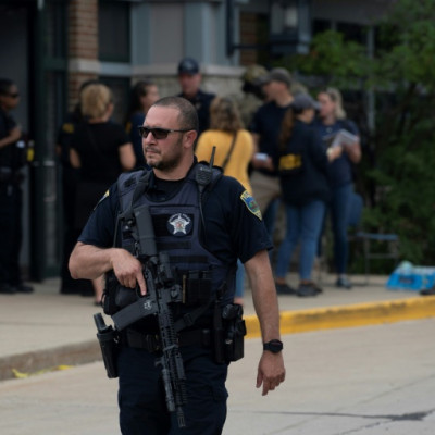A police officer searches the scene of the Fourth of July parade shooting in Highland Park, Illinois on July 4, 2022