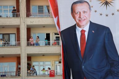 People watch an election rally of Turkish President Tayyip Erdogan from a building in Mardin