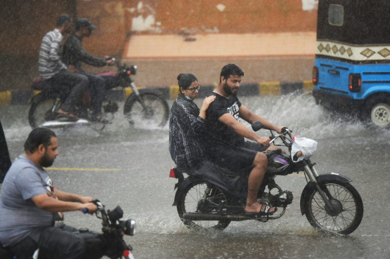 Les navetteurs conduisent des motos le long d'une rue pendant une pluie de mousson à Karachi