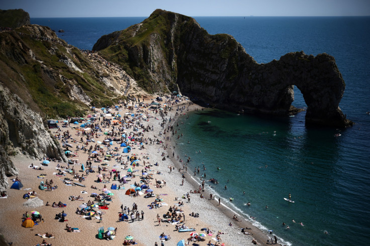 People visit Durdle Door Beach during warm weather