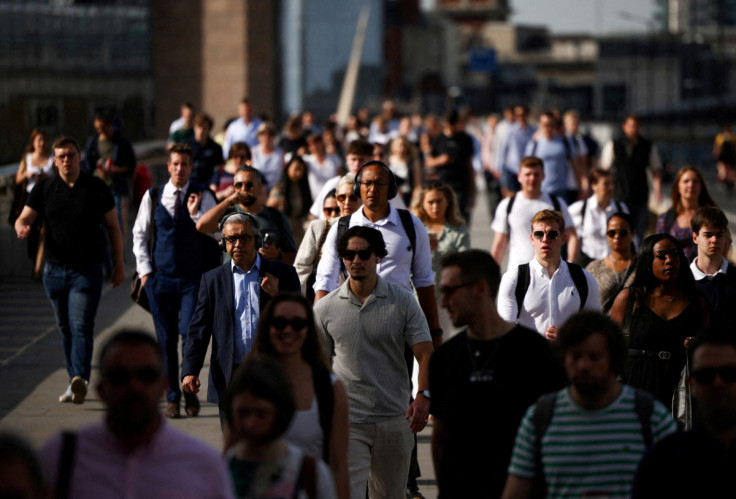 Commuters walk over London Bridge during warm weather in London