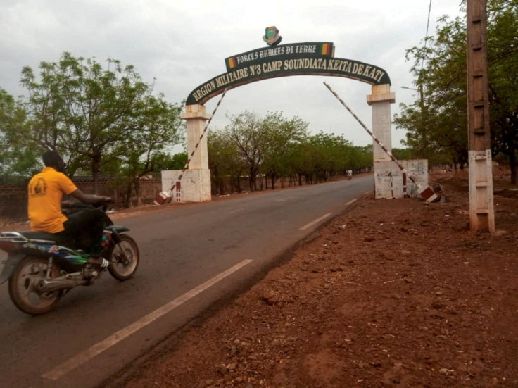 A man rides a motorcycle as he drives past the entrance of the Malian army force base in Kati