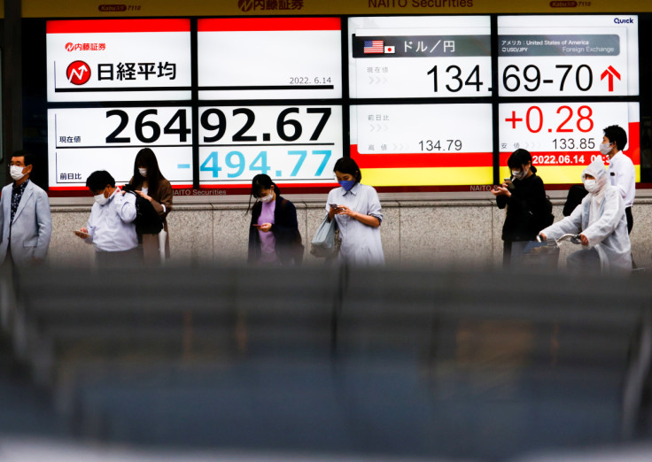 Passersby are seen in front of a screen displaying the Japanese yen exchange rate against the U.S. dollar and Nikkei share average in Tokyo