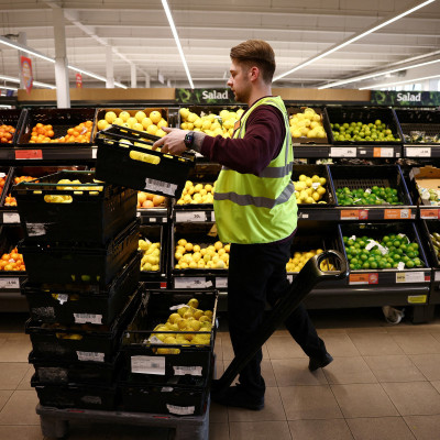 A employee arranges produce inside a Sainsbury’s supermarket in Richmond, west London