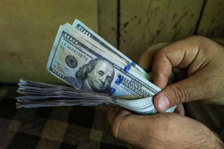 A trader counts U.S. dollar banknotes at a currency exchange booth in Peshawar
