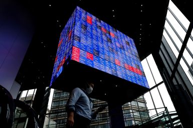 A man walks under an electronic screen showing Japan's Nikkei share price index inside a conference hall in Tokyo