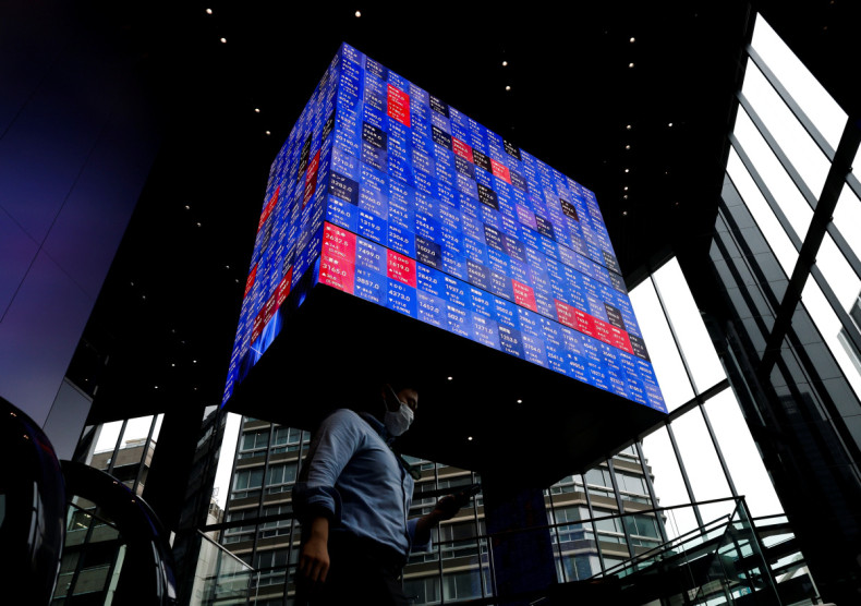 A man walks under an electronic screen showing Japan's Nikkei share price index inside a conference hall in Tokyo