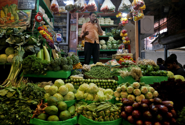  vegetable vendor, speaks on his mobile phone at a retail market area in Kolkata