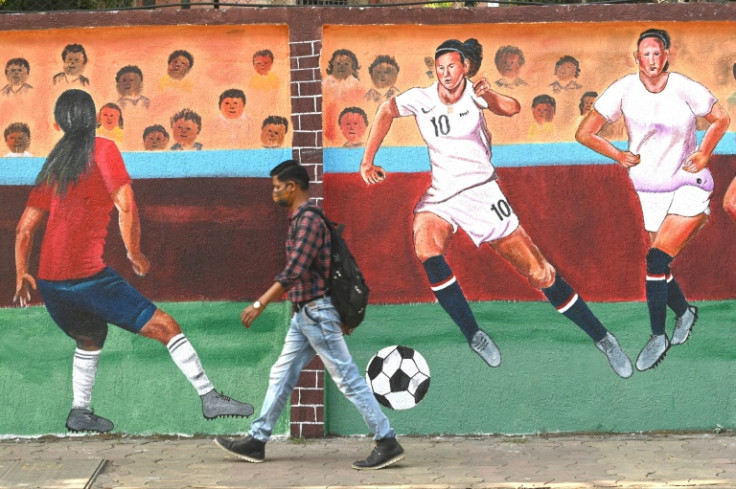 A pedestrian walks past a women's football mural  in Navi Mumbai in January