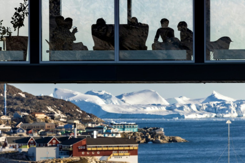 Les touristes prennent un verre assis sur un pont d'observation surplombant les icebergs flottant dans la baie de Disko, Ilulissat, dans l'ouest du Groenland