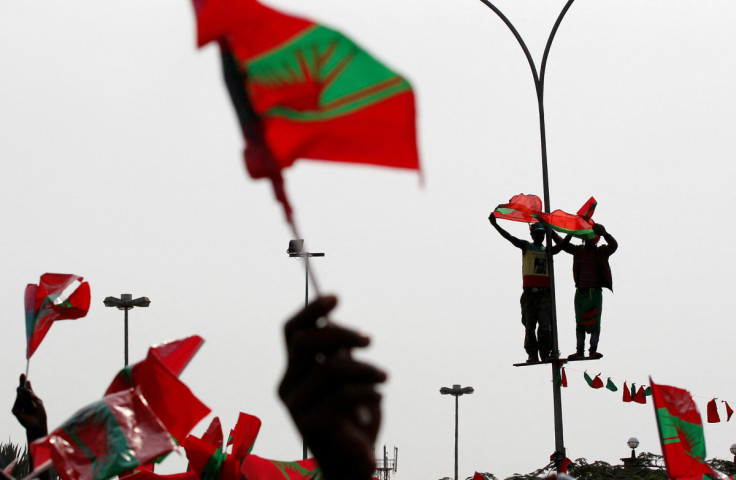 Supporters of Angola's main opposition UNITA party stand on a lamppost as they wave flags during an election rally in Luanda