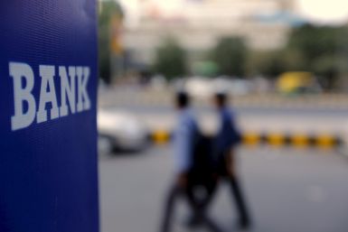 File photo of commuters walking past a bank sign along a road in New Delhi