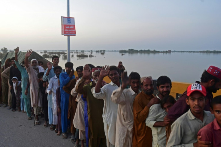 Men queue for food packets on an elevated highway in flooded Sindh