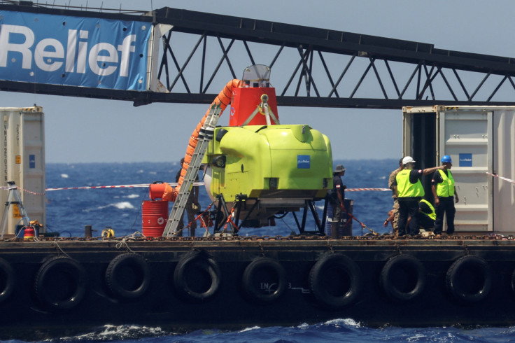 Technical personnel stand near a submarine in Tripoli