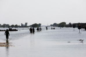 People walk amid rising flood waters on the Indus highway, following rains and floods during the monsoon season in Mehar