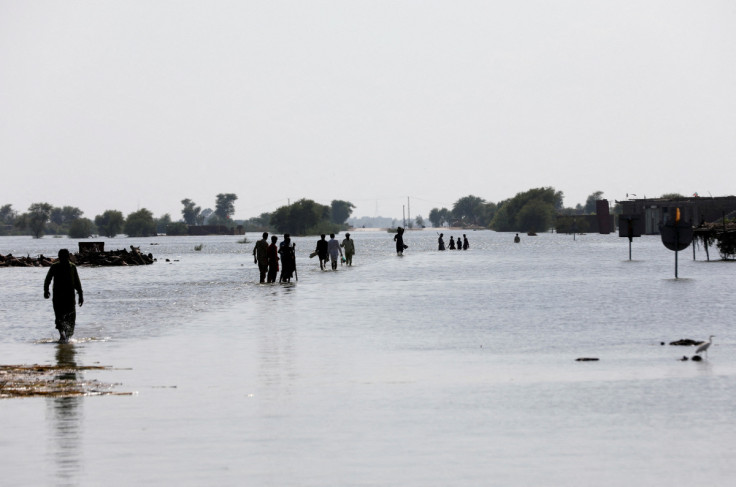 People walk amid rising flood waters on the Indus highway, following rains and floods during the monsoon season in Mehar