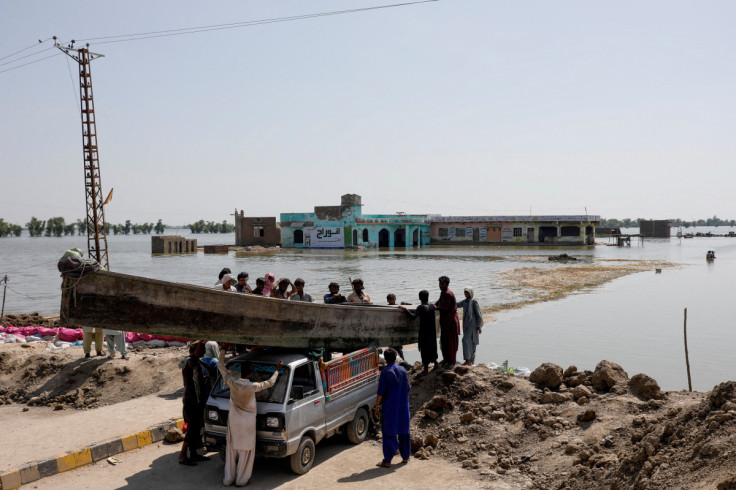 People launch a wooden boat into rising flood waters on the Indus highway, following rains and floods during the monsoon season in Mehar