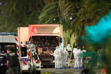 French police forces and forensic officers stand next to a truck that ran into a crowd celebrating the Bastille Day national holiday on the Promenade des Anglais killing at least 60 people in Nice