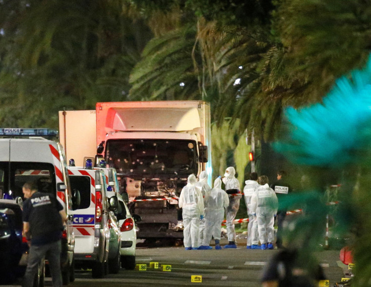 French police forces and forensic officers stand next to a truck that ran into a crowd celebrating the Bastille Day national holiday on the Promenade des Anglais killing at least 60 people in Nice