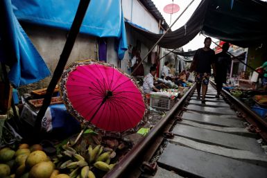 A woman walks at the Maeklong market next to the train tracks, on the outskirts of Bangkok