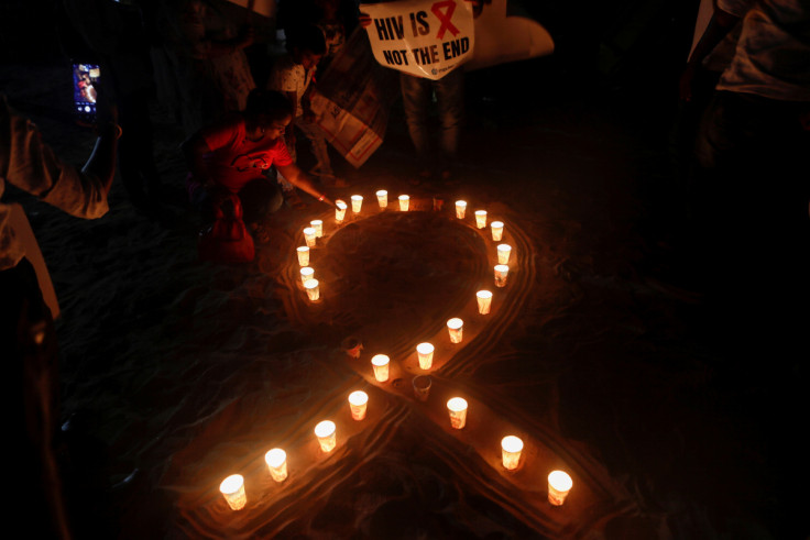 A woman arranges candles in the formation of a ribbon, the symbol for the solidarity of people living with AIDS on World AIDS Day on a beach in Mumbai