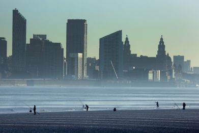 People fish in front of the skyline of Liverpool on the banks of the River Mersey in Wallasey