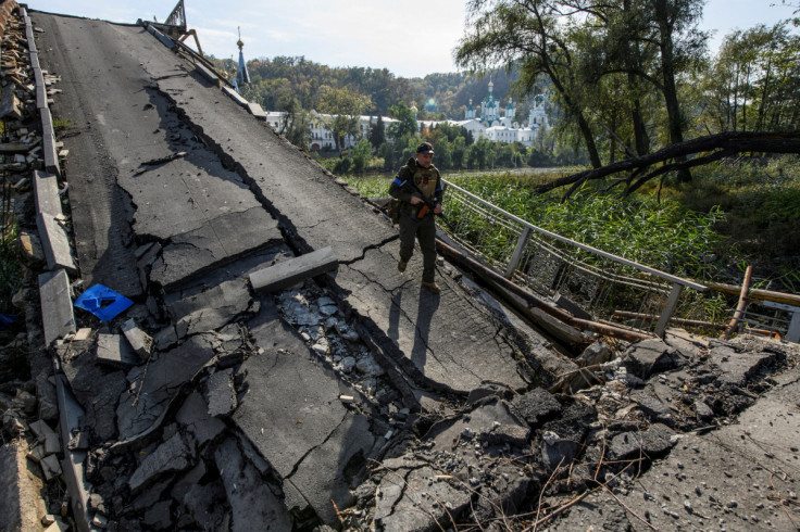 यूक्रेन के नेशनल गार्ड के सेवा सदस्य Sviatohirsk शहर में Siverskyi Donets नदी पर एक नष्ट पुल पर चलता है