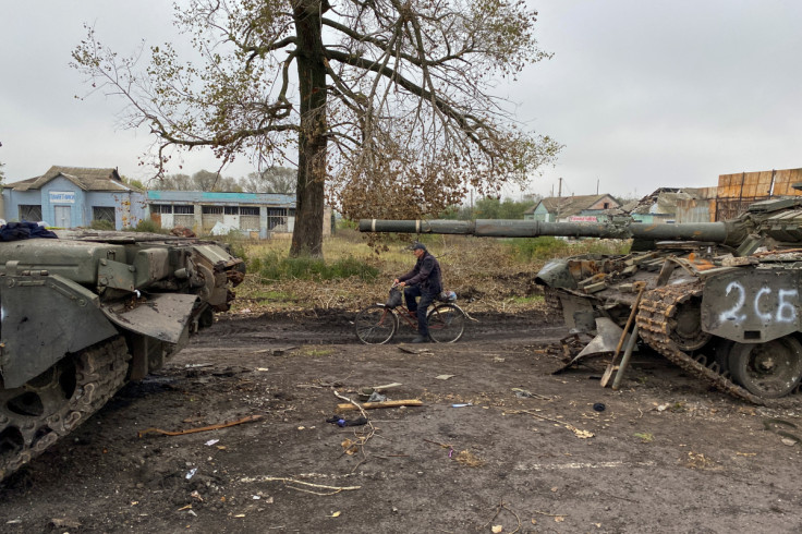 Local resident rides a bicycle past abandoned Russian tanks in the village of Kurylivka