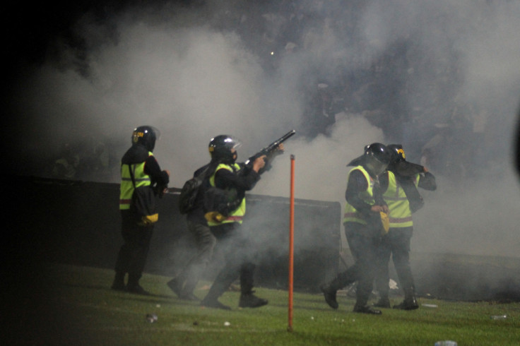 A riot police officer fires tear gas during a riot after the league BRI Liga 1 football match between Arema vs Persebaya at Kanjuruhan Stadium in Malang