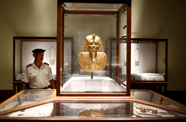 An Egyptian police officer looks at the Funeral Mask of King Psusennes I displayed inside a glass cabinet at the Egyptian Museum in Cairo
