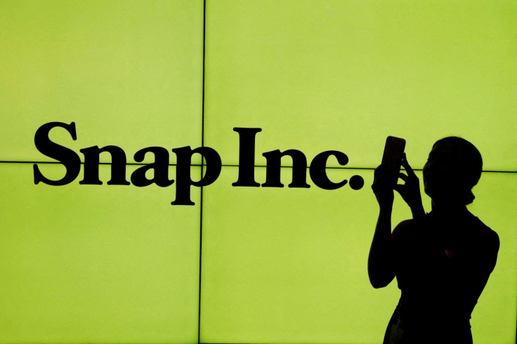 A woman stands in front of the logo of Snap Inc. on the floor of the New York Stock Exchange