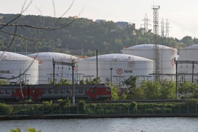 A train moves past oil tanks of the NNK-Primornefteproduct petroleum depot in the port of Vladivostok