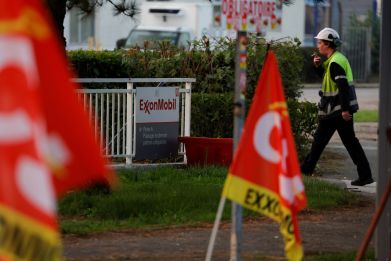 A worker walks past CGT trade union flags in front of the ExxonMobil oil refinery in Port-Jerome-sur-Seine