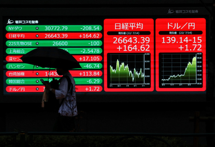 A man is silhouetted as he walks in front of a monitor displaying the Japanese yen exchange rate against the U.S. dollar and Nikkei share average in Tokyo, Japan