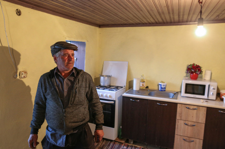 Tudorel Dedu, 52, looks at a light bulb inside his house in Vasilati