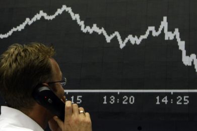 A trader talks on the phone as he stands in front of the DAX board at the Frankfurt stock exchange