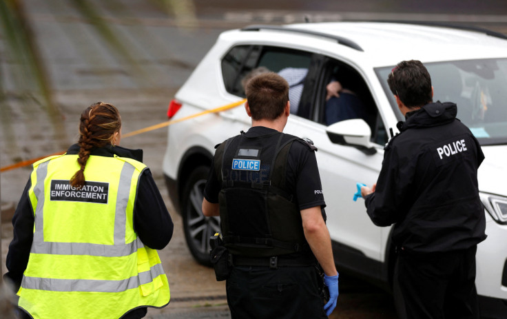 Immigration and police officers stand next to a car believed to have been used in a petrol bomb attack on the Border Force processing centre in Dover