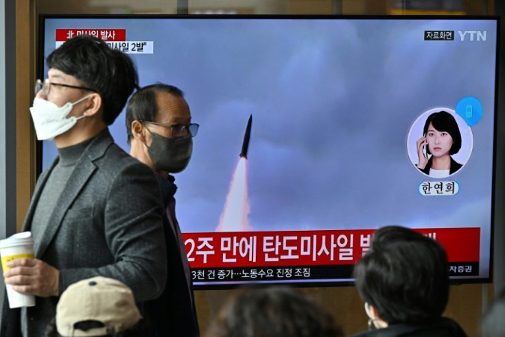 People watch a television screen showing a news broadcast with file footage of a North Korean missile test at a railway station in Seoul on October 28