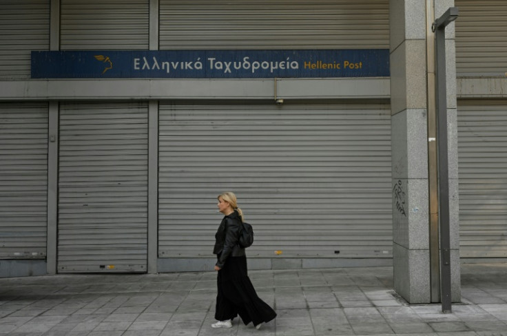 A woman walks past a closed post office during a 24-hour strike in Athens