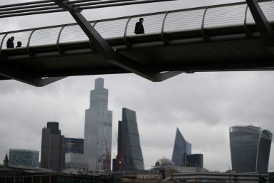 People walk across Millennium Bridge with the City of London financial district seen behind, amid the coronavirus disease (COVID-19) pandemic, in London