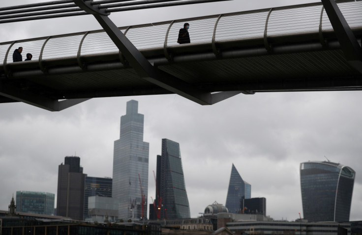 People walk across Millennium Bridge with the City of London financial district seen behind, amid the coronavirus disease (COVID-19) pandemic, in London